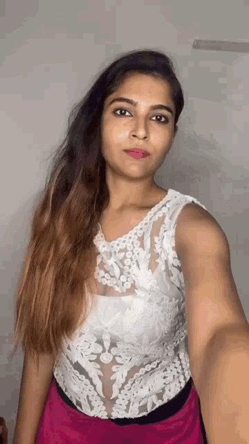the woman is wearing a white top and a pink skirt .