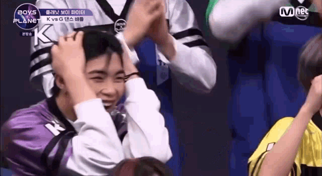 a group of people are sitting in a stadium and one of them is holding another person 's head .