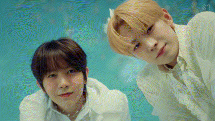 two young men in white shirts are standing next to each other .