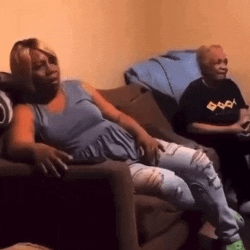 a woman is sitting on a couch while a man sits on a couch playing a video game .
