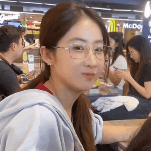 a woman wearing glasses is sitting in front of a mcdonald 's