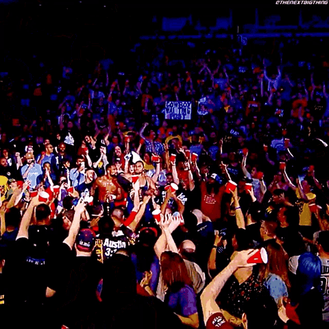 a wrestler is holding a trophy in front of a crowd with red cups