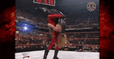 a wrestler is doing a handstand on top of another wrestler in a ring .