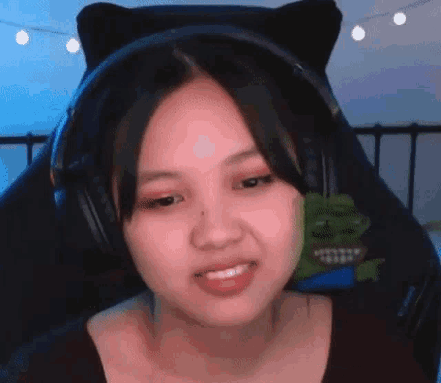 a young girl wearing headphones and cat ears is sitting in a gaming chair .