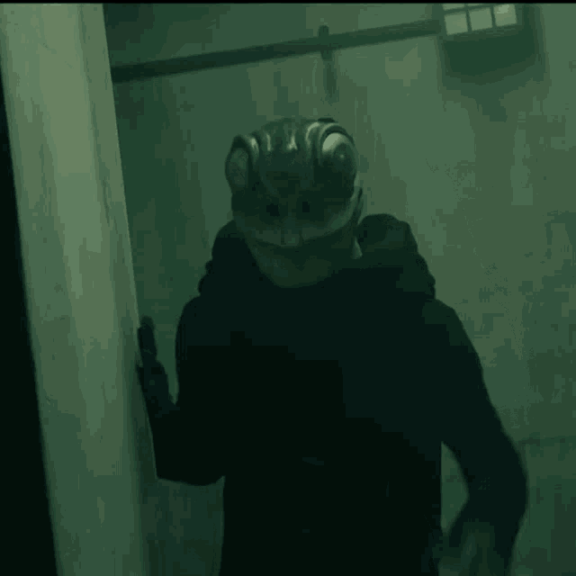 a person with a lizard mask on their head waving