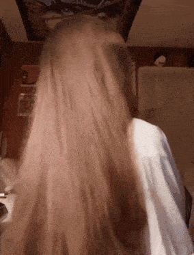 a woman with very long blonde hair is standing in front of a wall with a picture on it