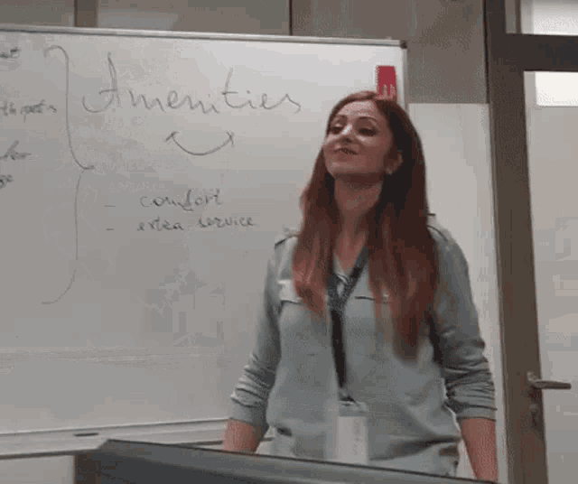 a woman is standing in front of a white board that says amenities