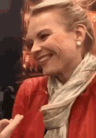 a woman wearing a scarf and earrings is smiling while sitting in front of a poster .