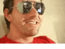 a man wearing a red shirt and sunglasses is smiling .