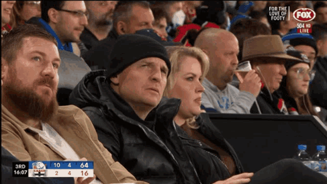 a group of people watching a game with a fox logo on the bottom