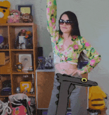 a woman wearing sunglasses and a floral shirt is standing in front of a shelf full of stuffed animals