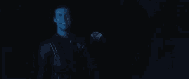 a man is smiling in the dark while holding a flashlight in his hand .