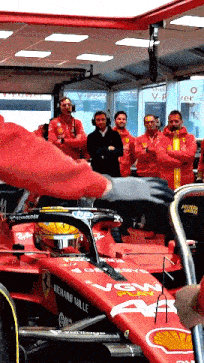 a man in a red jacket is working on a red race car