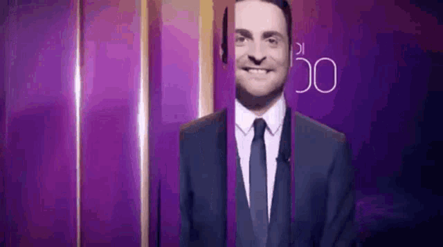 a man in a suit and tie is smiling in front of a purple background with the number 50 on it