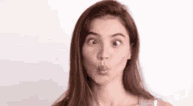 a woman is making a funny face with her mouth open and looking at the camera .