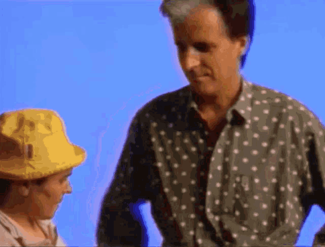 a man in a polka dot shirt stands next to a little boy in a yellow hat
