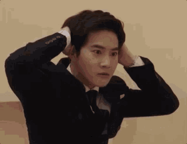 a man in a suit and tie is holding his hair .