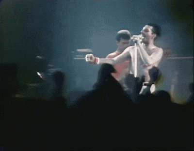 a man singing into a microphone while another man stands behind him