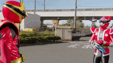 two red superheros are standing on a street with a sign that says stop