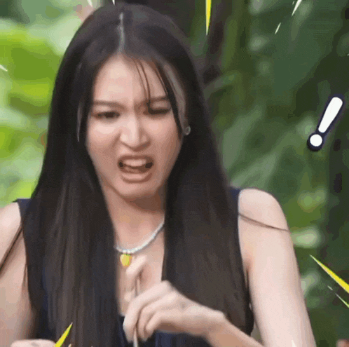 a woman with long hair is making a funny face while wearing a necklace .