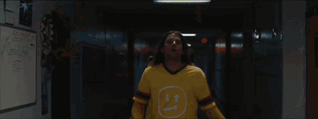 a man in a yellow shirt stands in a hallway next to a sign that says ' nc state '