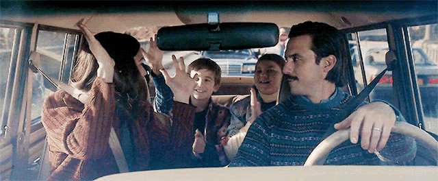 a man is driving a car with a group of people in the back seat .