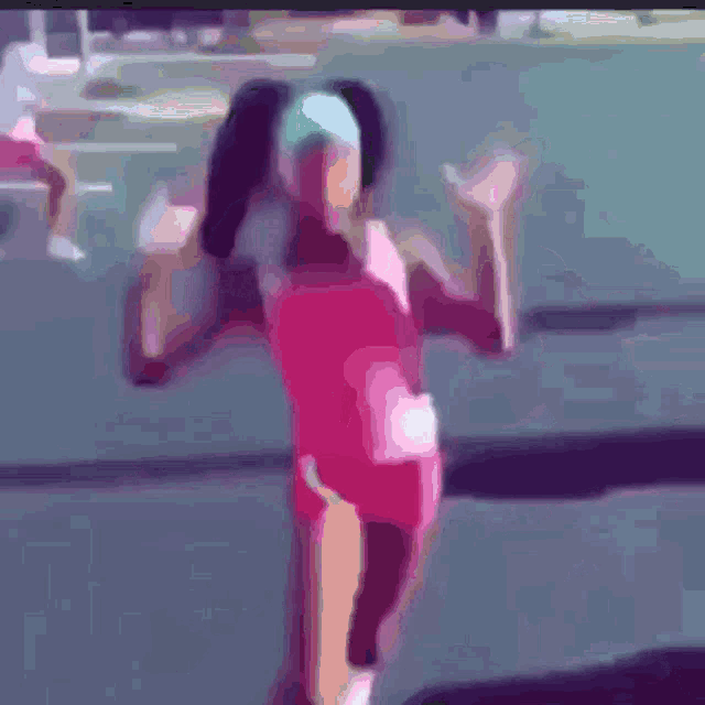 a girl in a pink leotard is standing on a track with her arms outstretched
