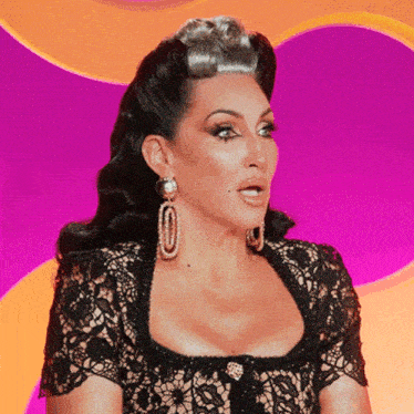 a woman wearing a black lace top and earrings is making a funny face