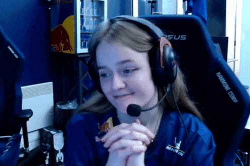 a girl wearing headphones and a shirt that says red bull is sitting in a gaming chair