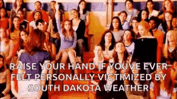 a large group of people are sitting in a stadium and raising their hands in the air .