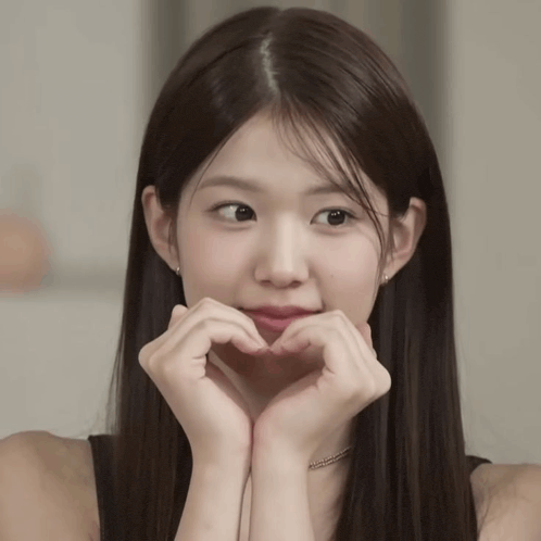 a woman making a heart shape with her hands on her face