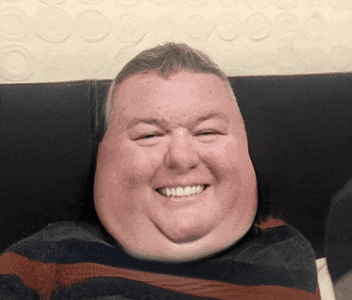a man with a big smile on his face is wearing a striped sweater