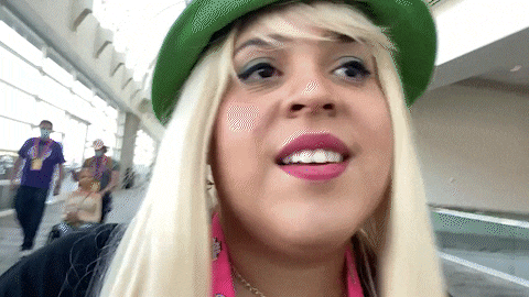 a woman with blonde hair wearing a green hat and pink lipstick