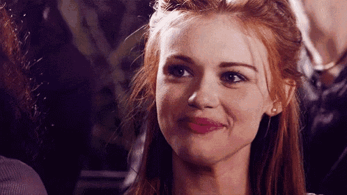 a close up of a woman 's face with red hair smiling .