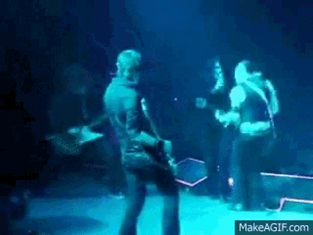 a group of people are standing on a stage playing guitars and singing .