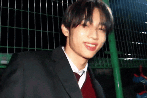 a young man in a suit and tie is smiling and looking at the camera .