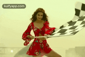 a woman in a red dress is waving a checkered flag .