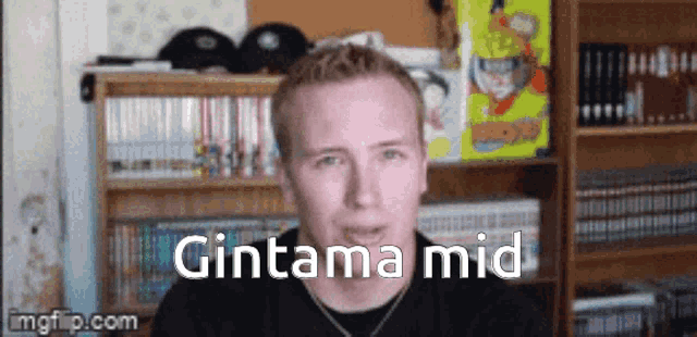 a man is standing in front of a bookshelf and says gintama mid