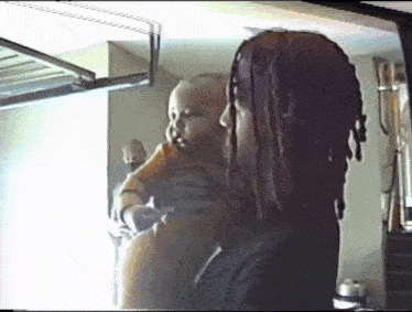 a man with dreadlocks holds a baby in his arms