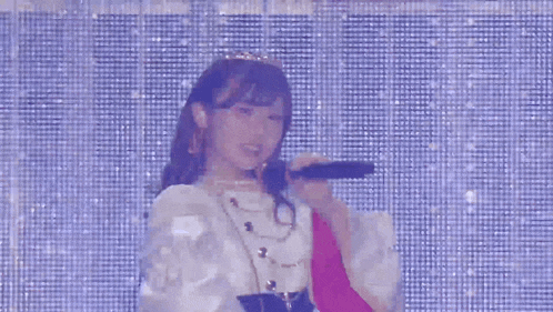a woman singing into a microphone in front of a blue background