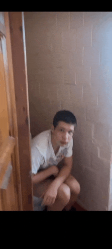 a young man is sitting on a toilet with his legs crossed and looking at the camera .