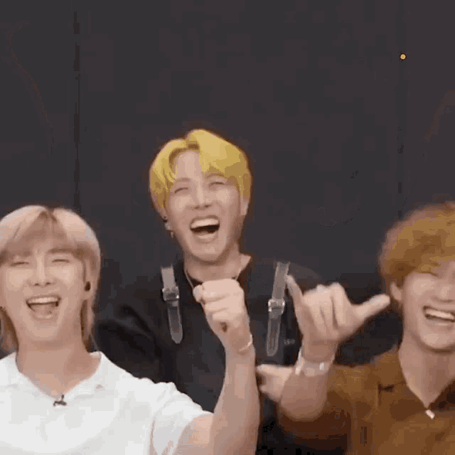a group of young men are laughing and making funny faces while standing next to each other .