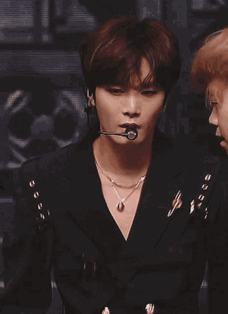 a close up of a man wearing a microphone and a black shirt