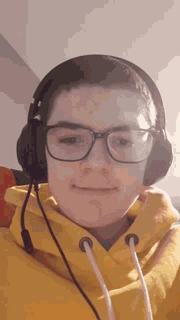 a young boy wearing glasses and headphones looks at the camera