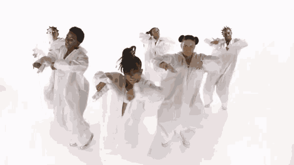 a group of people in white clothes are dancing on a white surface .