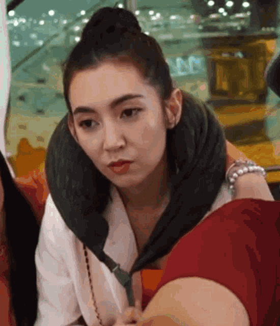 a woman with a neck pillow around her neck is sitting next to another woman .