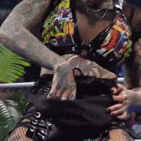 a woman with a lot of tattoos on her arms is standing in a boxing ring