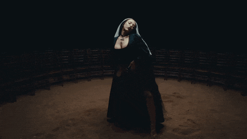 a woman in a nun costume is standing in a dark room with chairs