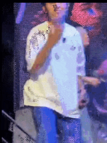 a man in a white shirt is singing into a microphone on stage
