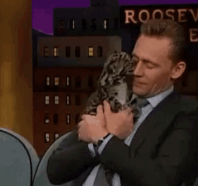 a man in a suit is holding a cat in front of a sign that says roosevelt